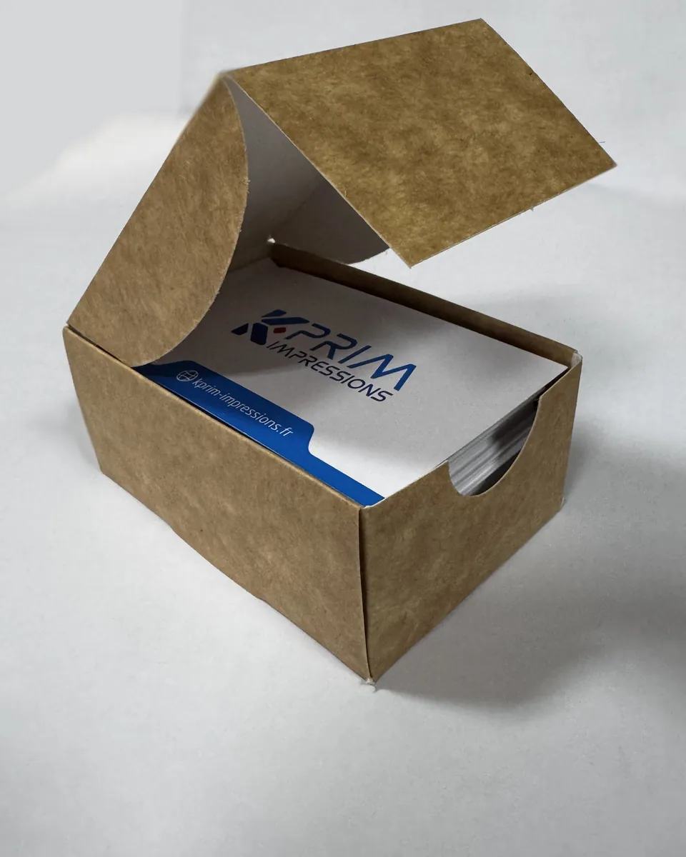 Une boîte en kraft ouverte, pleine de cartes de visite Kprim Impressions